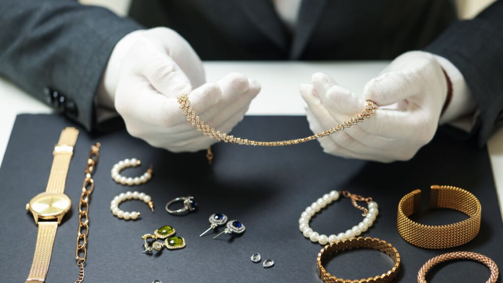 an examiner doing a jewelry inspection of various jewelry pieces on a table with white gloves