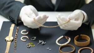 an examiner doing a jewelry inspection of various jewelry pieces on a table with white gloves