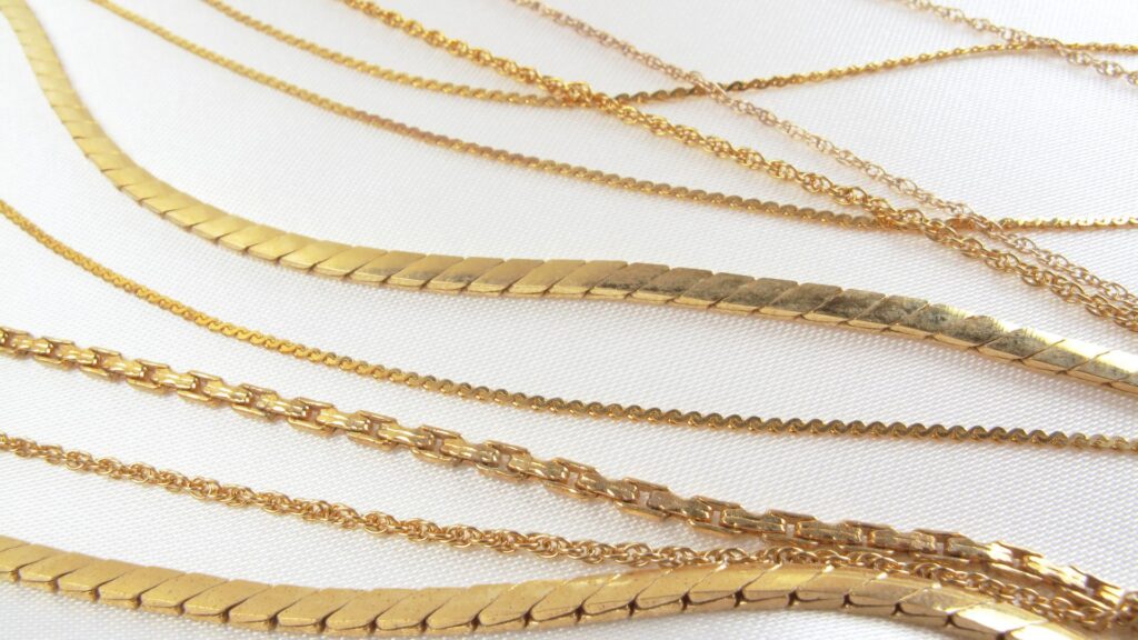an image of various yellow gold chains laying on a table to show comparison of each other
