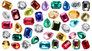 a background image of various gemstones being shown including sapphire, emerald, and rubies