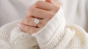 an image of a womens hands in a longsleeve sweater displaying an engagement ring on her finger